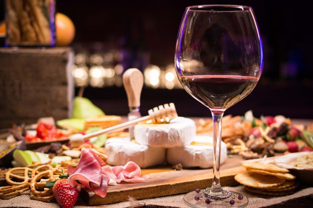 Planche de fromages et charcuterie avec un verre de vin rouge